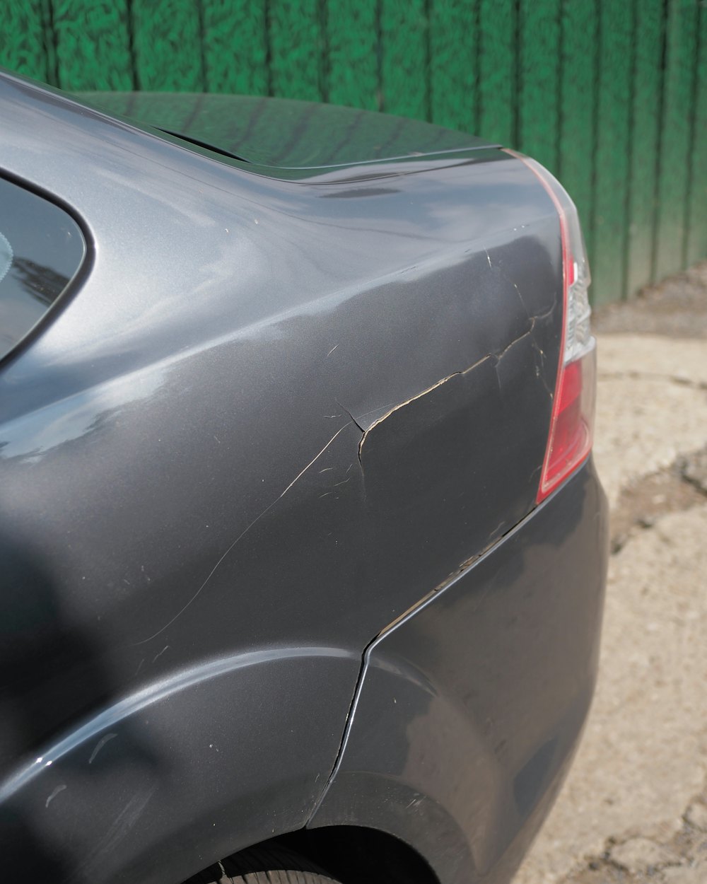 Close-up of a dented and scratched grey rear quarter panel