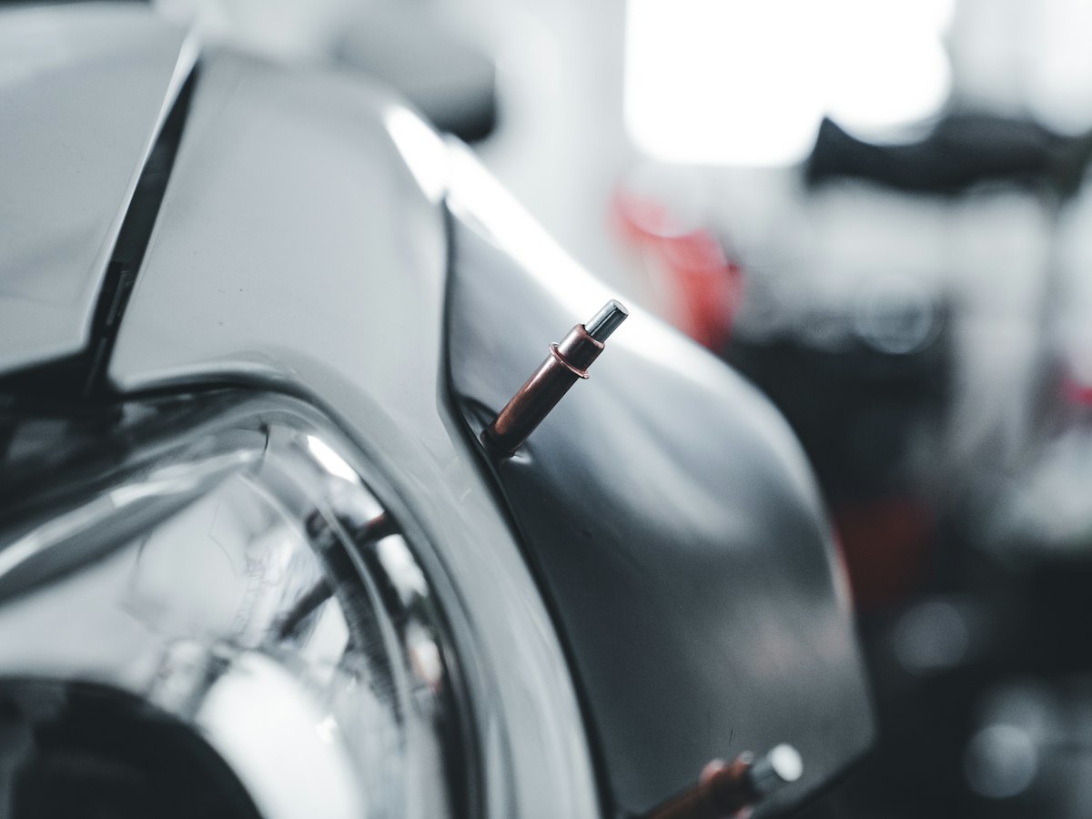 Close-up of a car body panel being worked on with a dent repair tool