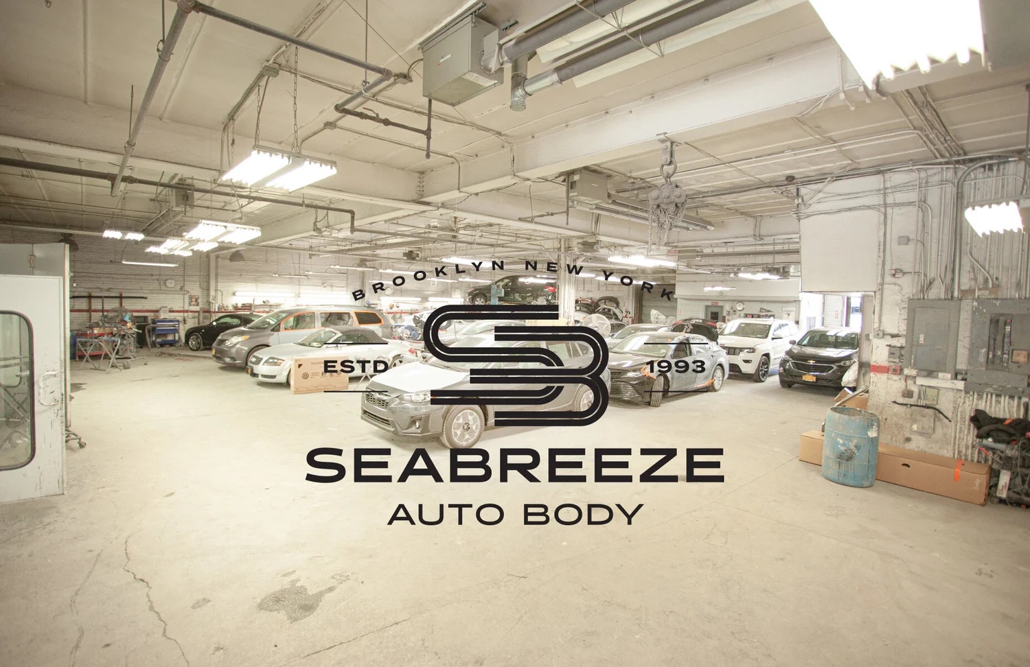 Inside the Sea Breeze Auto Body shop floor with cars in for repair